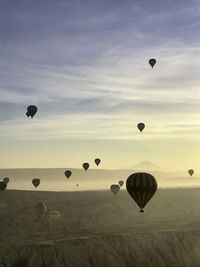 Hot air balloons flying over landscape against sky