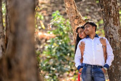 Young couple standing by trees in forest