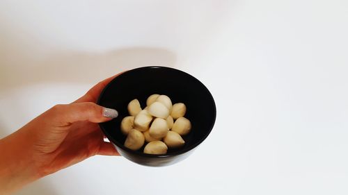 Close-up of hand holding bowl over white background