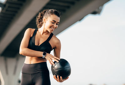 Young woman exercising with medicine ball while standing outdoors