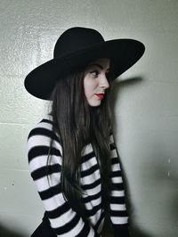 Portrait of beautiful young woman standing against wall