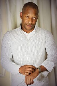 Portrait of man wearing wristwatch against curtain