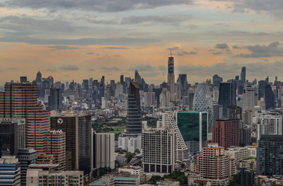 Aerial view of buildings in city against cloudy sky