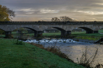 Arch bridge over river against sky in city