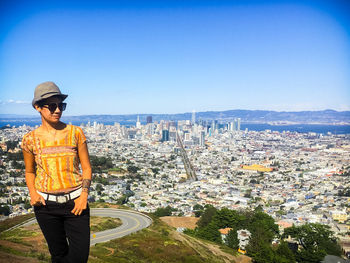 Woman standing by cityscape against sky