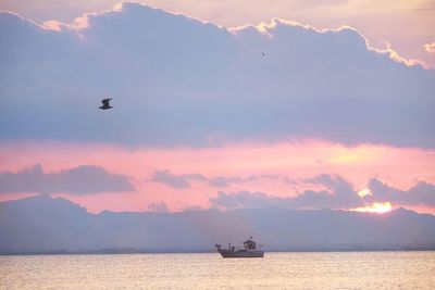 Silhouette boat sailing in sea against sky during sunset