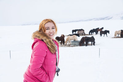 Portrait of smiling woman with horse standing on snow field against sky