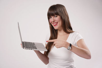 Portrait of young woman holding hair over white background