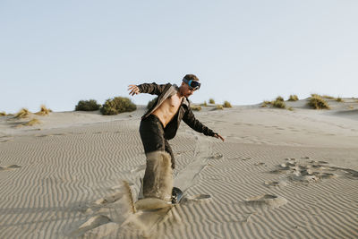 Young man snow boarding on sand at almeria, tabernas desert, spain