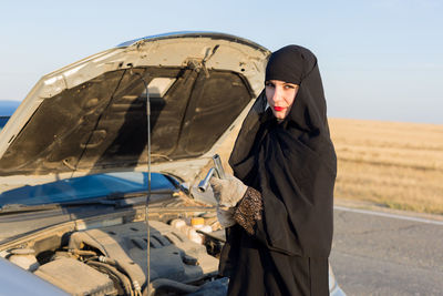 Woman standing on car against the sky