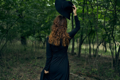 Rear view of woman standing in forest