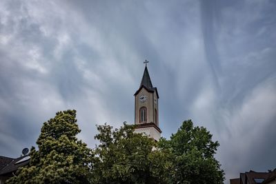 Low angle view of trees and building against sky