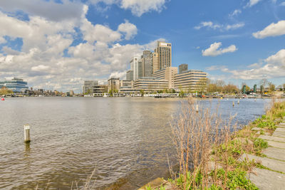 Buildings by river against sky