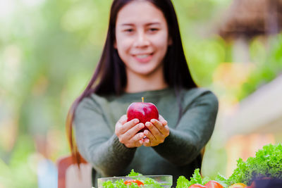 Midsection of woman holding strawberry outdoors