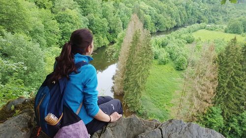 Rear view of woman sitting on mobile phone in forest