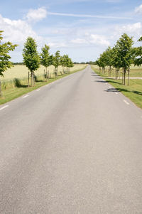 Empty road amidst trees against sky