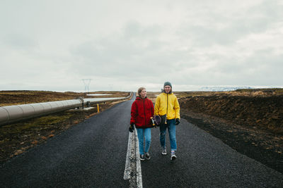 Rear view of people standing on road against sky