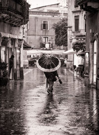 Man walking on wet street in city