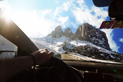 Cropped hand man driving car against sky