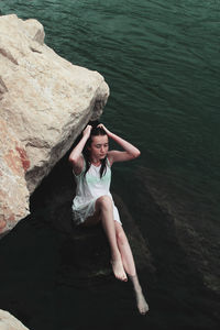 High angle portrait of young woman standing on rock by river
