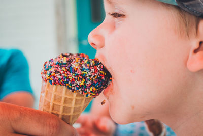 Cropped hand feeding ice cream to boy