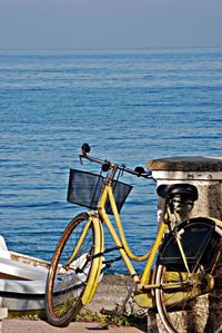 Bicycle by sea against sky