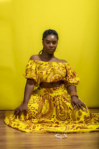 Young beautiful woman, serious, looking at the camera, sitting on a wooden floor. 