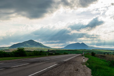 Road leading towards mountains against sky