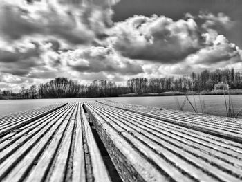 View of wooden boardwalk against cloudy sky