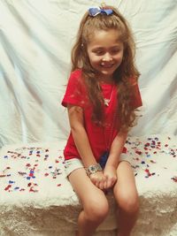 Happy girl sitting on seat against white backdrop