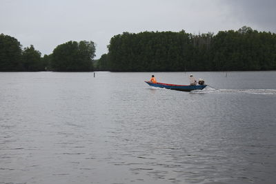 People on boat in river against sky