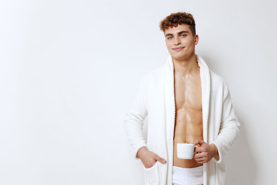 Portrait of young man standing against white background