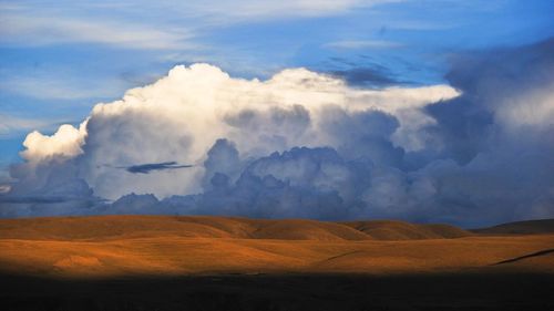 Scenic view of dramatic landscape against storm clouds