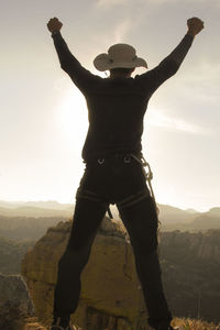 Rear view of man standing on mountain against sky