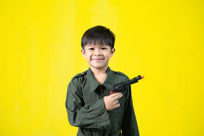 Portrait of smiling boy standing against yellow background