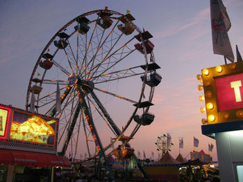 Low angle view of ferris wheel in city against sky during sunset