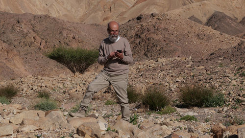 Senior man using smart phone in the desert 