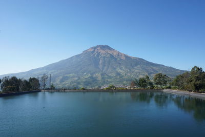 Scenic view of lake and mountains against clear blue sky