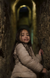 Portrait of girl standing amidst stone wall