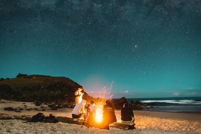 People on beach against sky at night