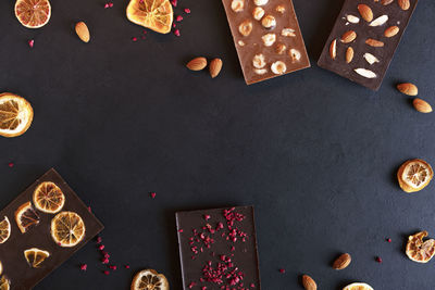 Organic chocolate bars with sublimated berries, orange slices, almond and hazelnut. copy space.