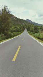 Empty road by mountain against sky