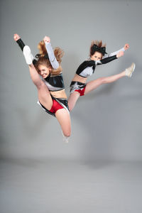 Low angle view of young woman dancing against white background