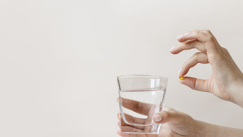 Midsection of woman holding glass against white background