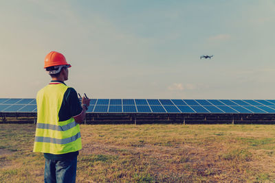 Rear view of engineer flying drone over solar panels