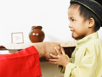 Cropped image of father holding son hand at home