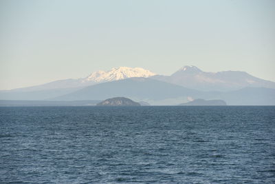 Scenic view of sea and mountains against clear sky