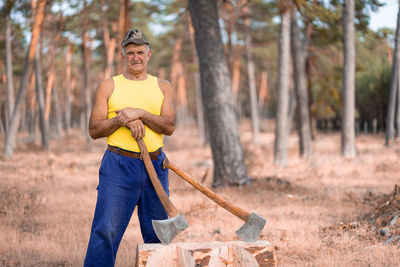 Full length portrait of man standing against trees in forest