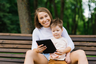 Young happy mom and a cute caucasian boy of three years, her son are emotionally talking online 