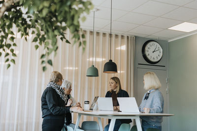 Smiling women using laptops in office